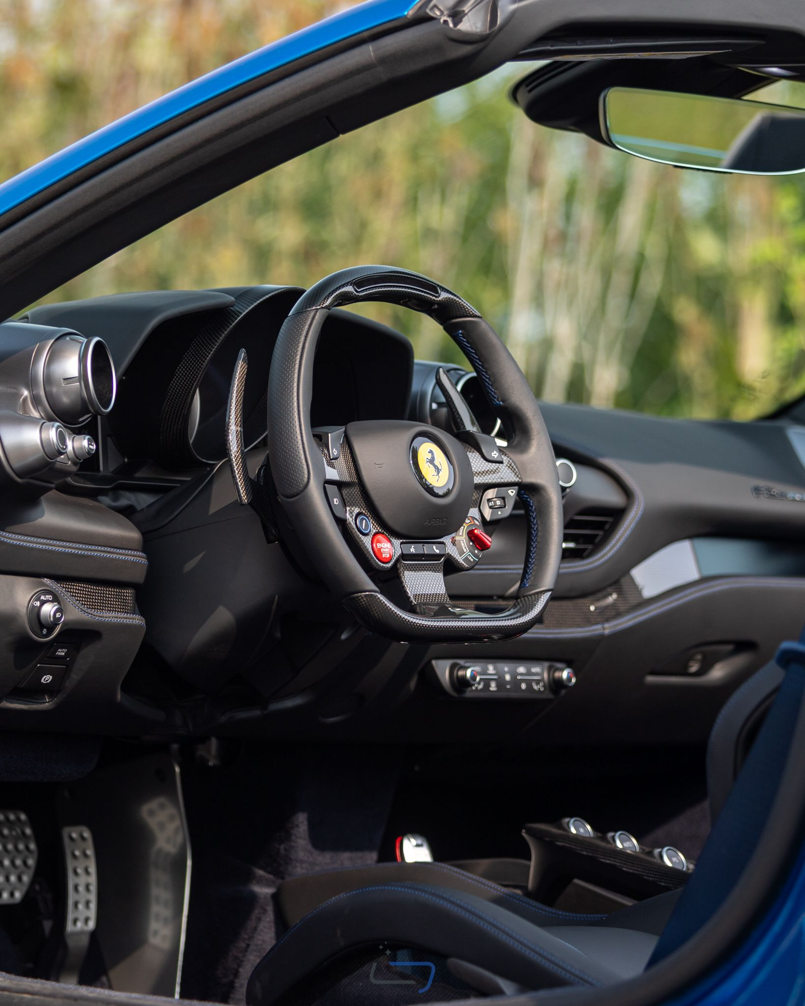 Ferrari sports car interior with black steering wheel and blue exterior door open