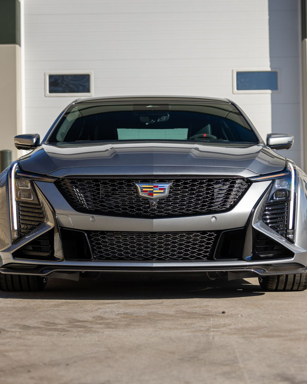Front view of a black Cadillac parked outside a garage door