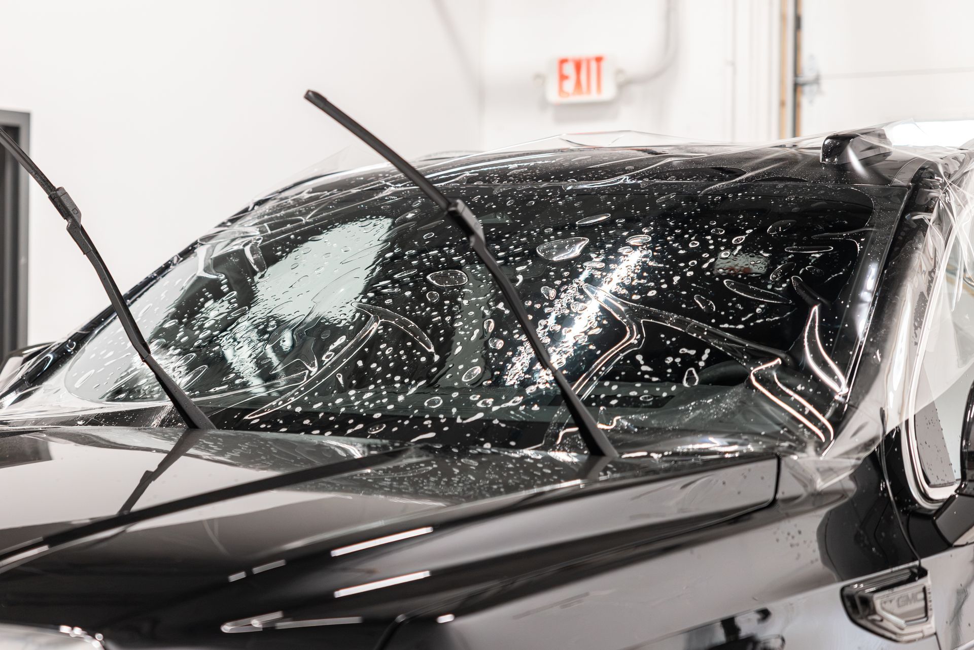 Car with shattered windshield and raised wipers inside a garage or service bay