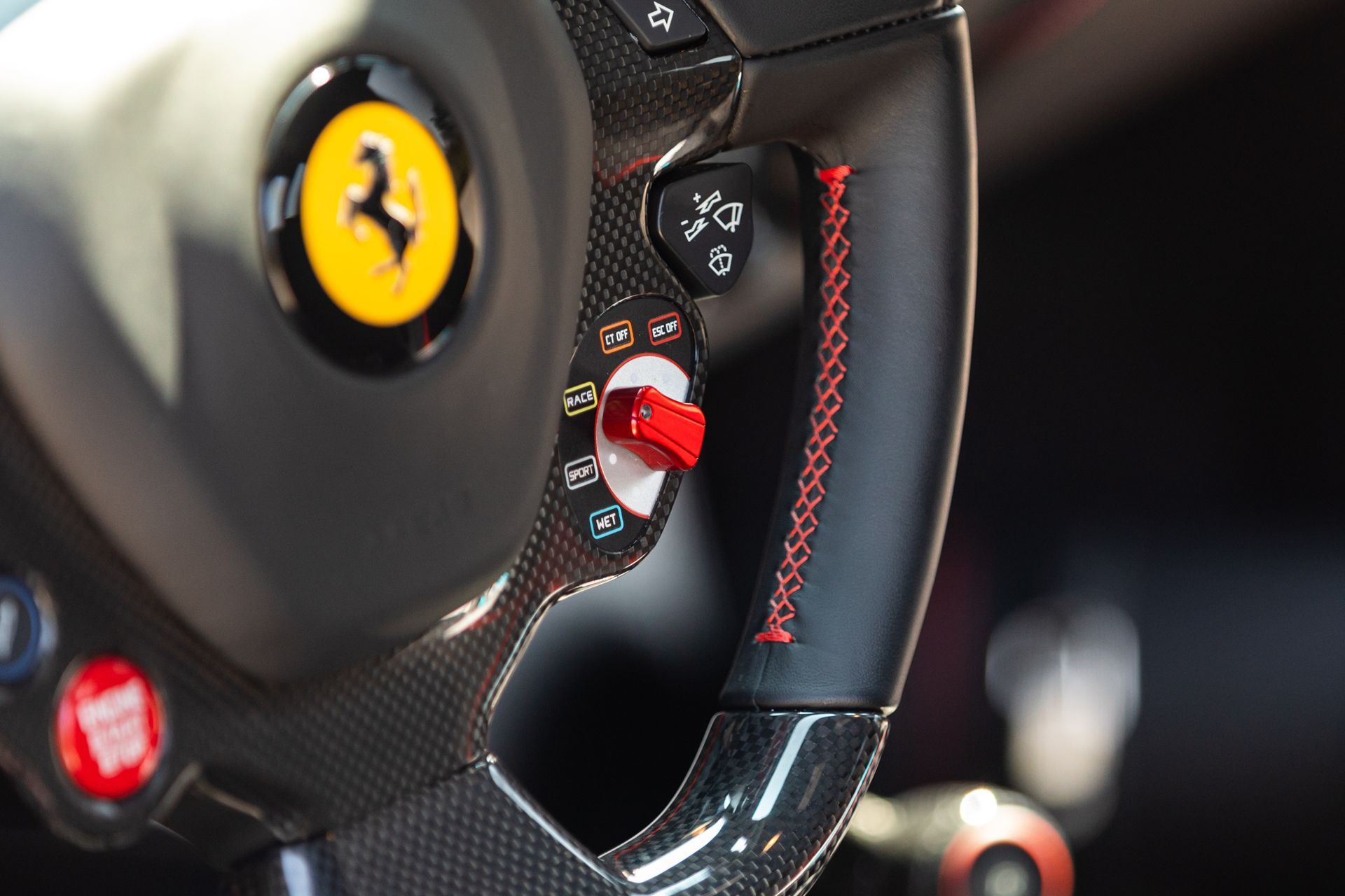 Close-up of a Ferrari steering wheel with carbon fiber and red trim