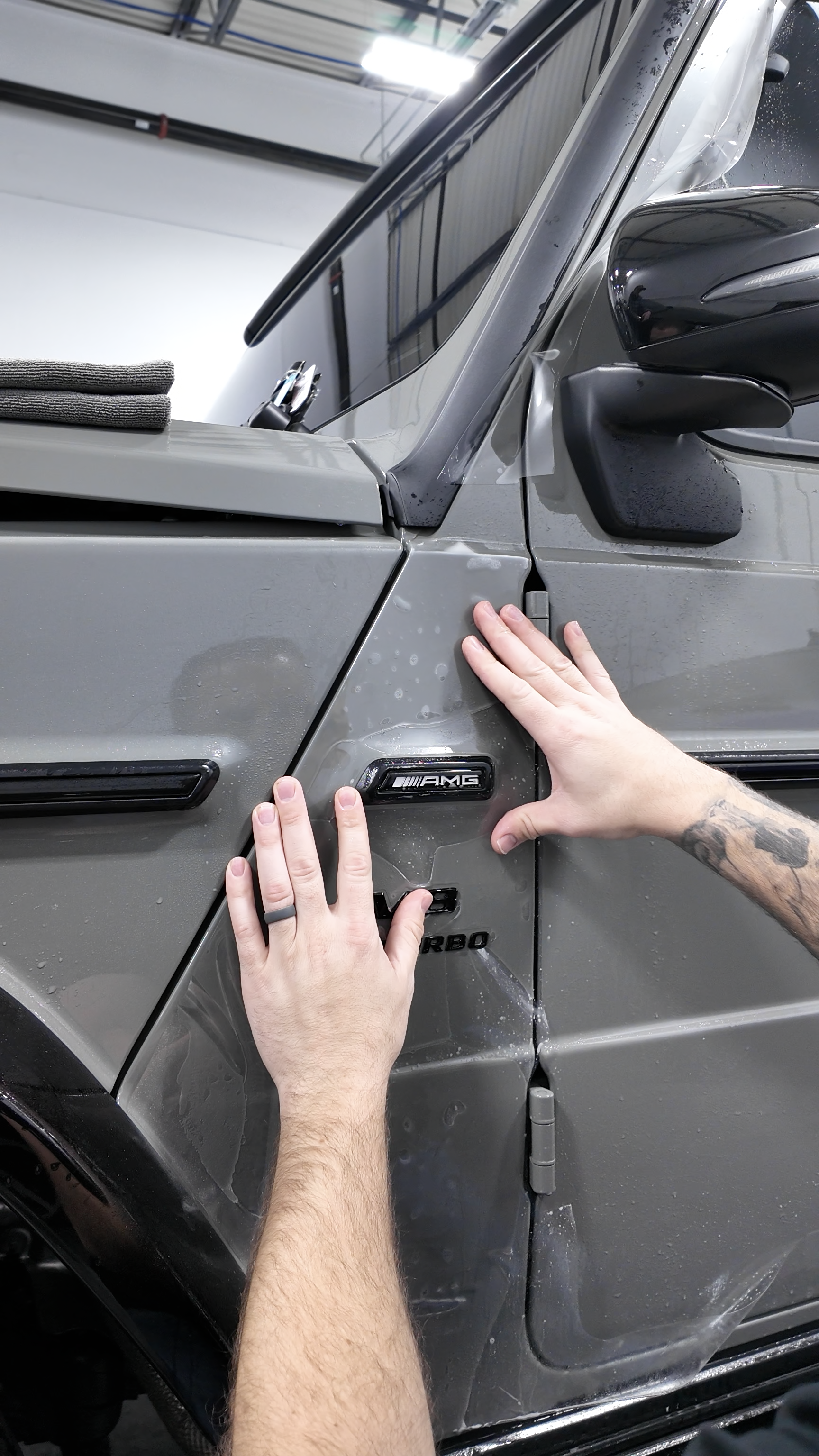 Man detailing a black BMW with a pink sponge in a car wash bay