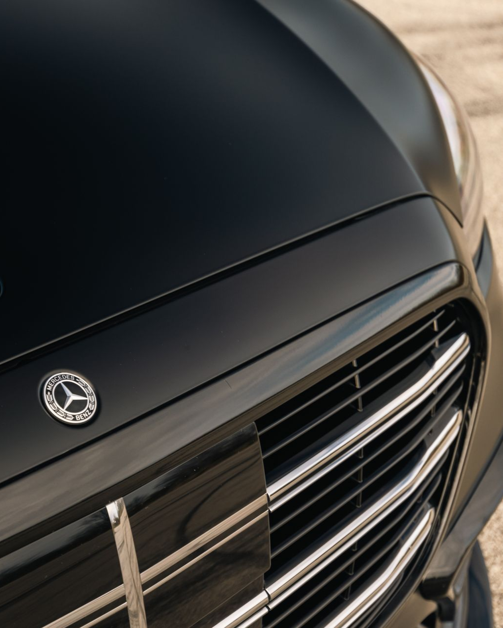 Close-up of a black car hood and chrome grille with a circular emblem