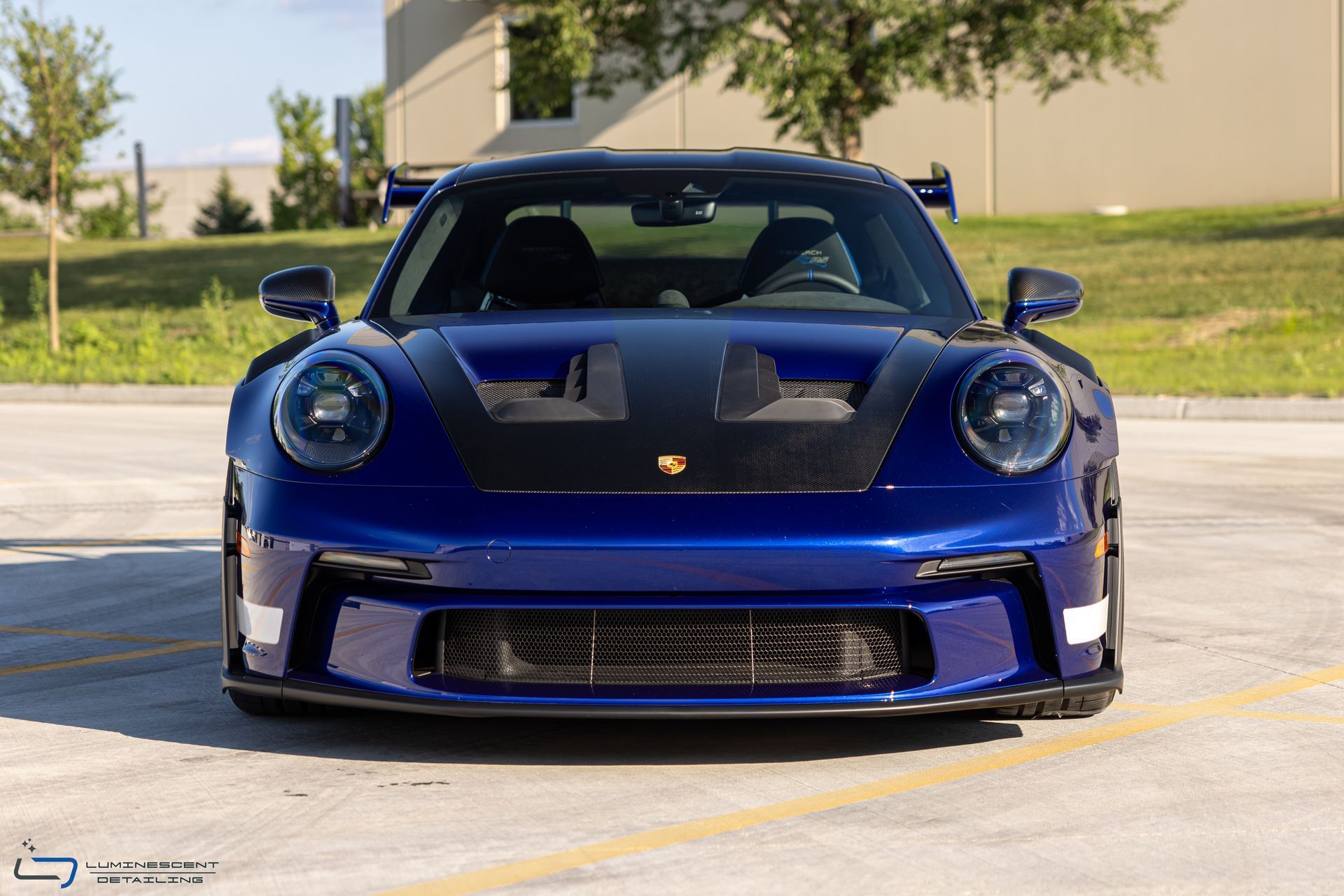 Blue Porsche sports car parked outdoors in front view on a sunny day