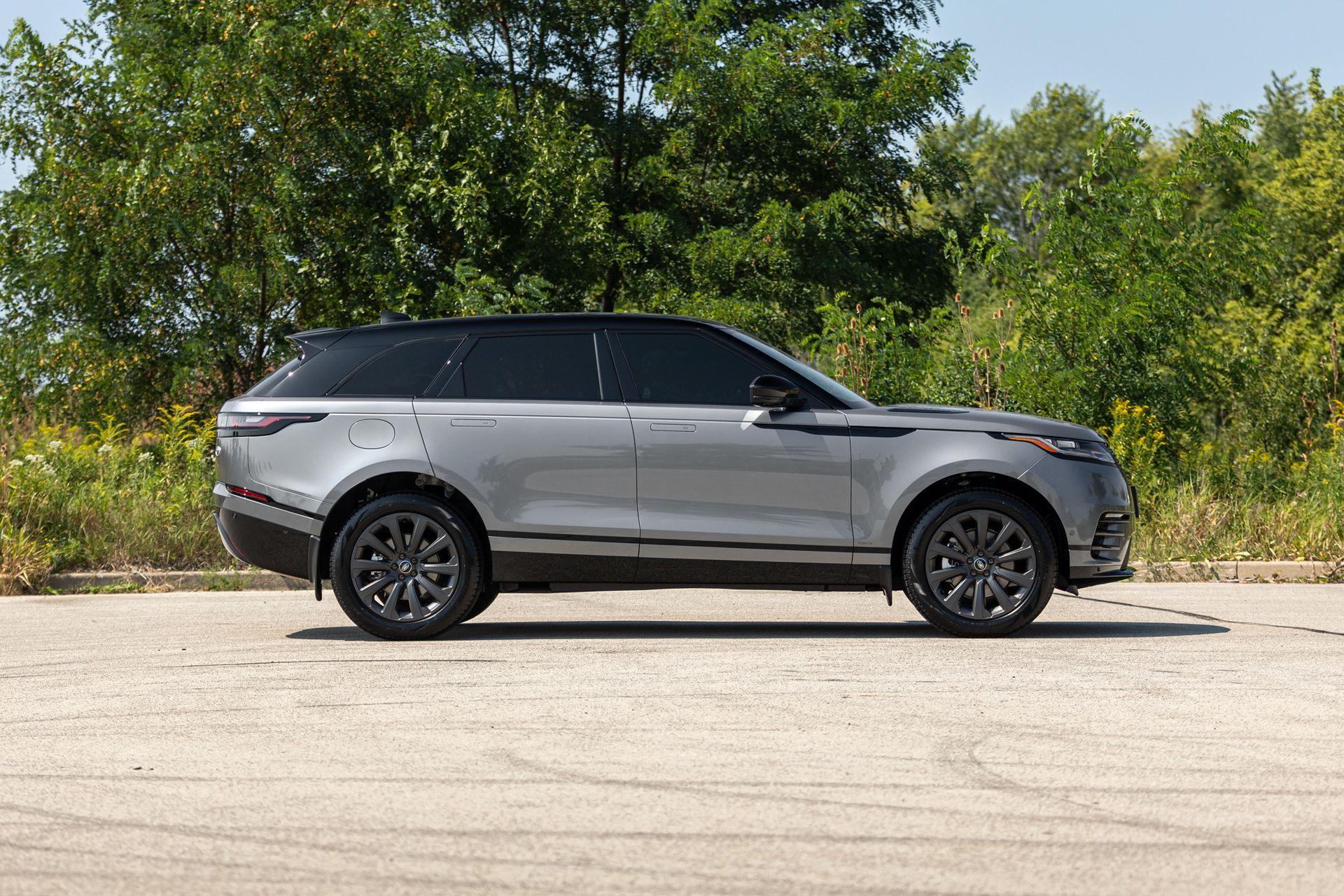 Silver SUV parked on pavement with trees in the background
