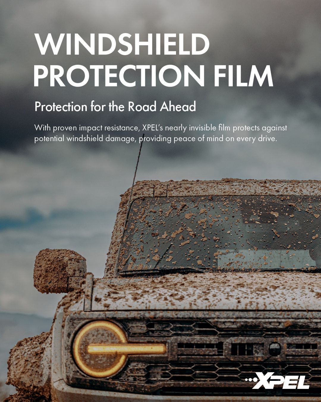 Mud-covered off-road truck with windscreen protection film ad text