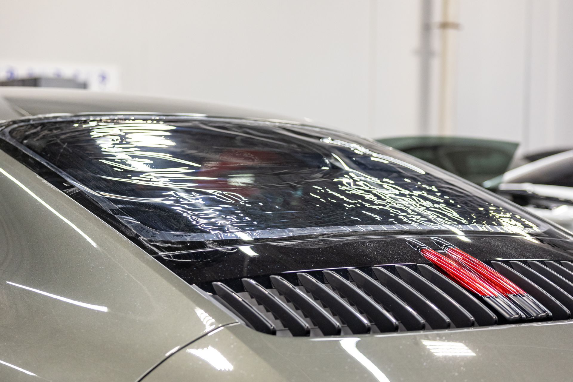 Rear view of a silver sports car with a black rear window and red taillight in a showroom