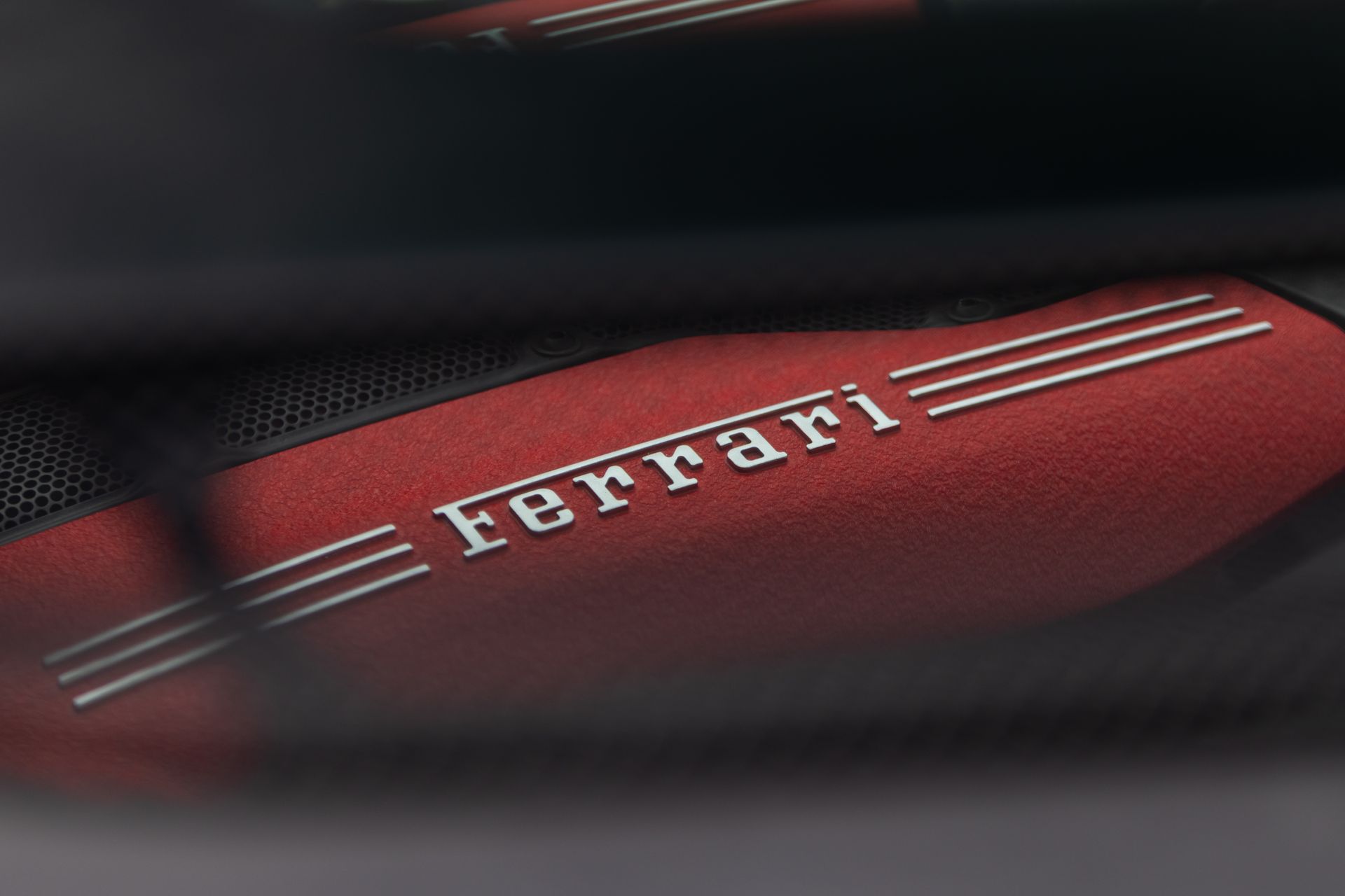 Close-up of a red Ferrari engine cover with white logo and silver stripes