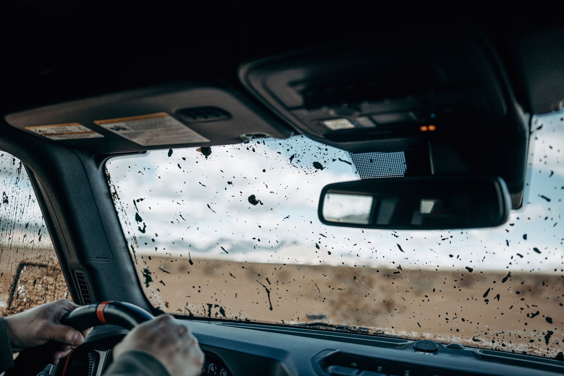 Driver's view through a rain-speckled windshield on a sandy road with a truck ahead