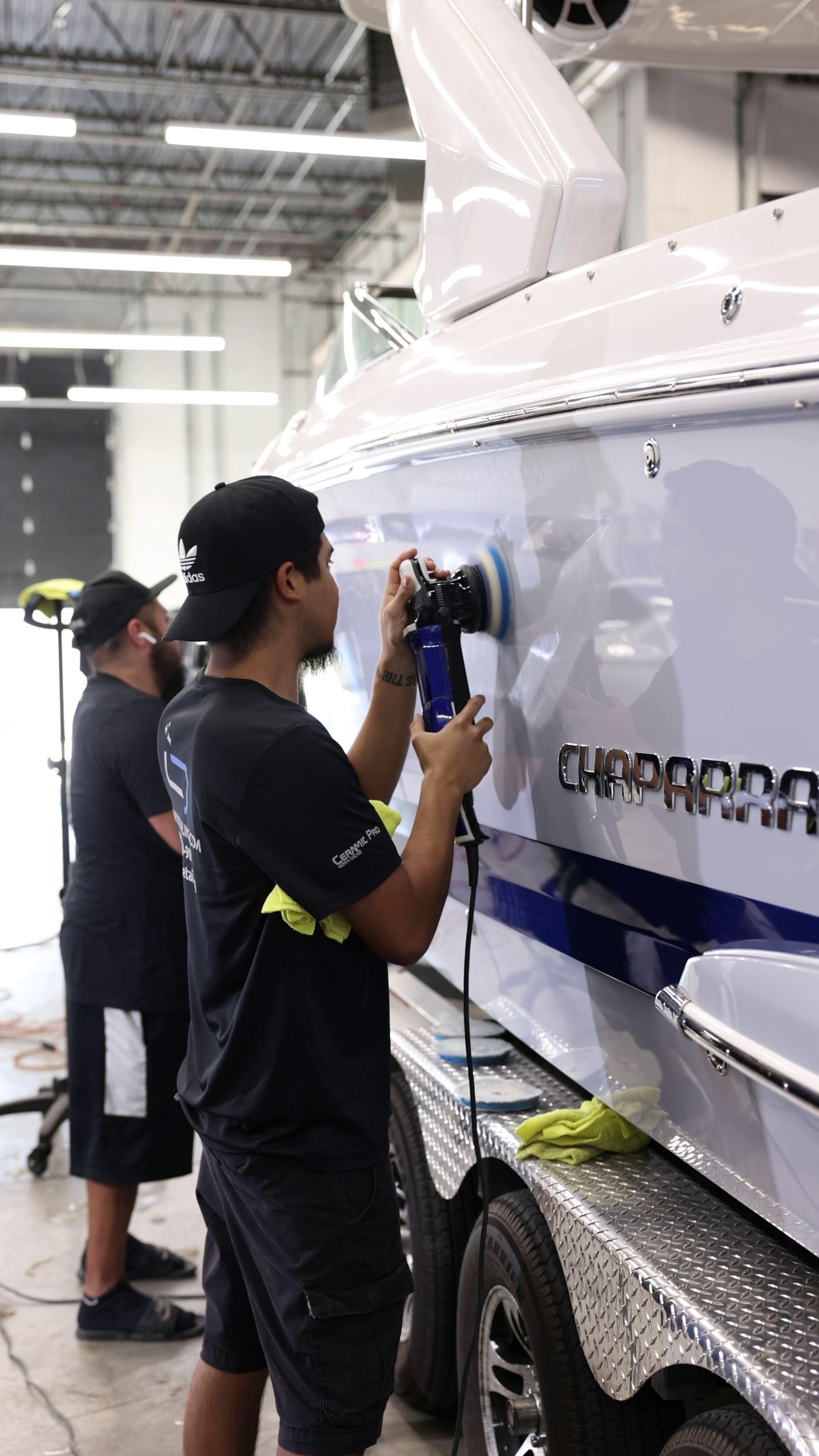 Technicians polishing a white boat hull in a workshop