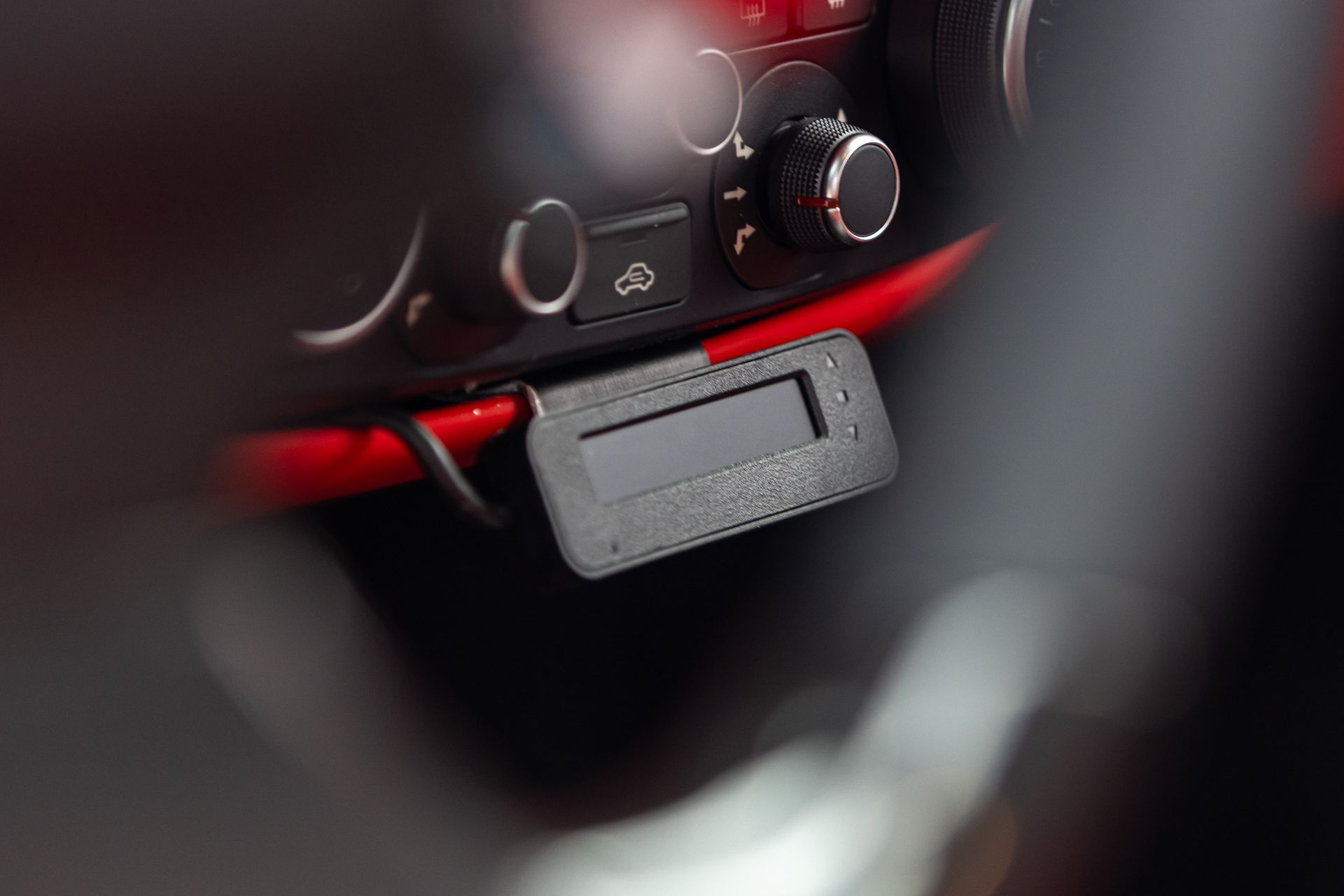Close-up of a car dashboard with a black and red key fob hanging from the ignition area