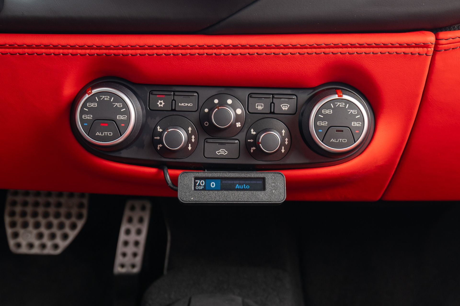 Car dashboard climate control panel with black knobs and a digital display on a red interior