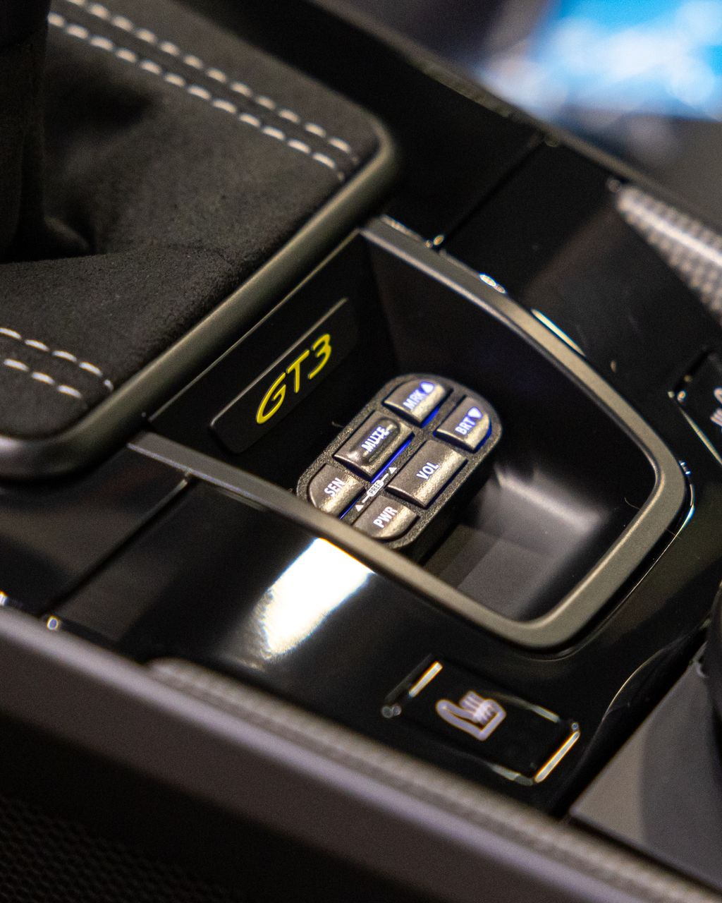 Close-up of a Porsche GT3 center console with drive mode buttons and glossy black trim
