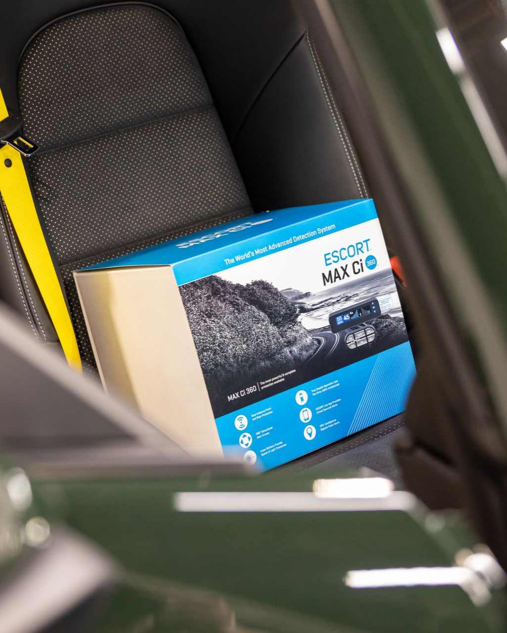 Blue box on a car seat beside a yellow seat belt in a vehicle interior