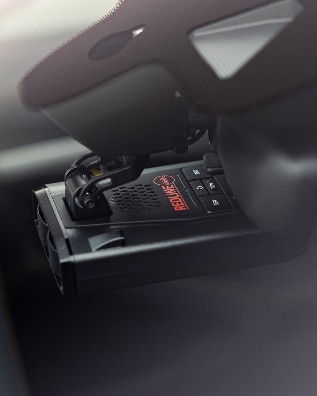 Black device with red display and cables mounted inside a car console compartment