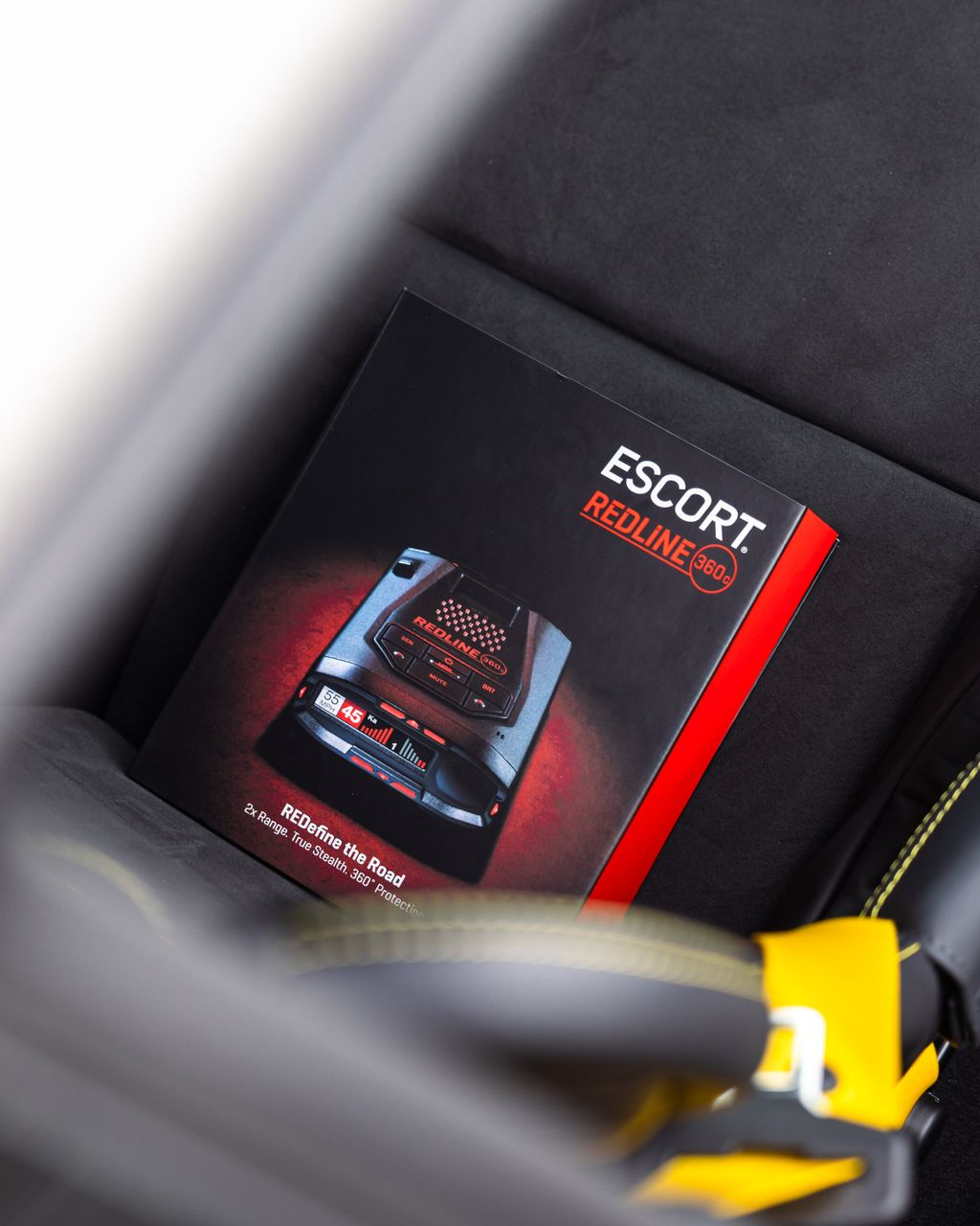 A black Escort Performance booklet with red accents resting in a car seat pocket