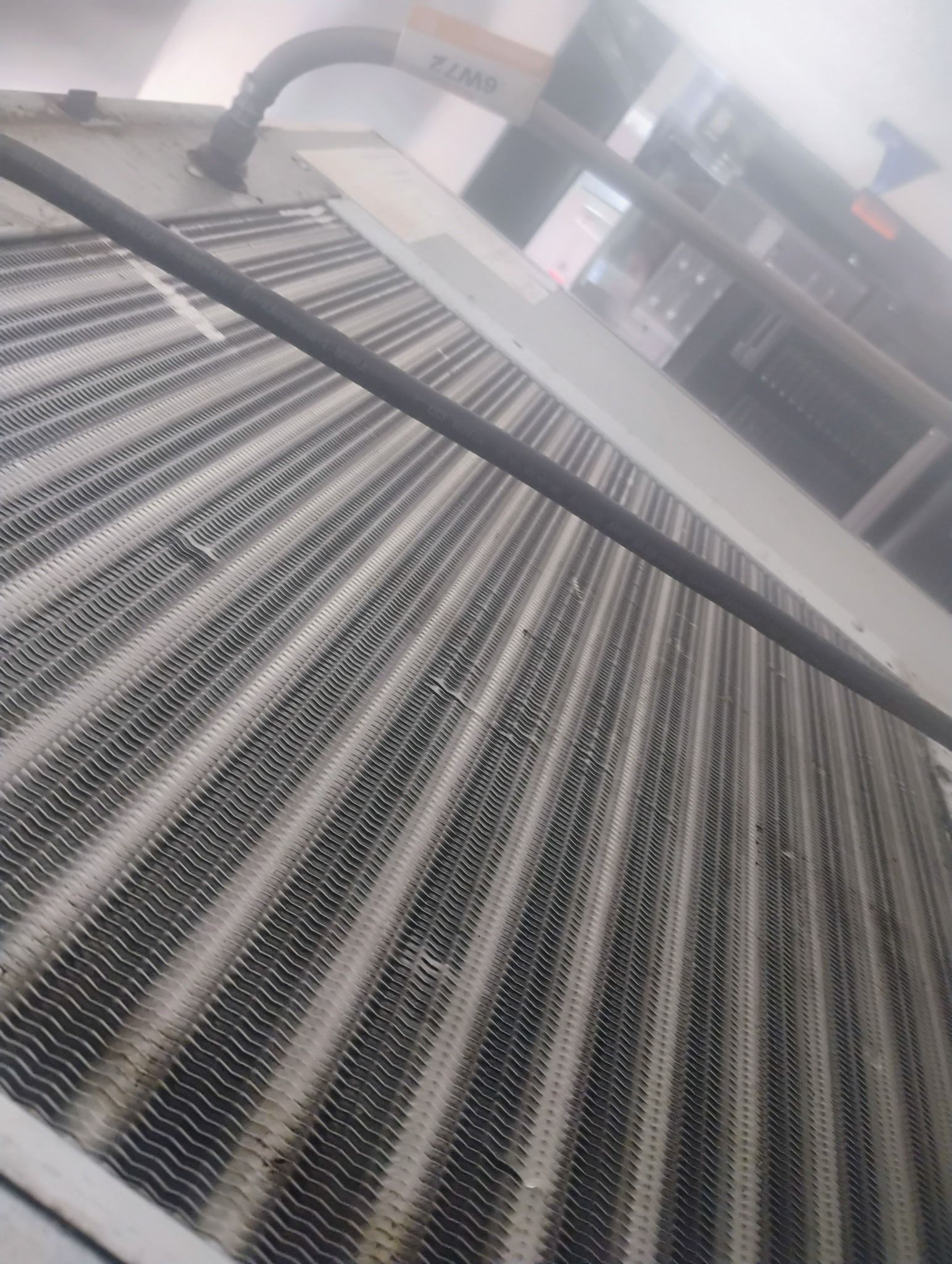 A close-up of a dirty, dusty metal air conditioning evaporator coil with visible buildup on the fins.