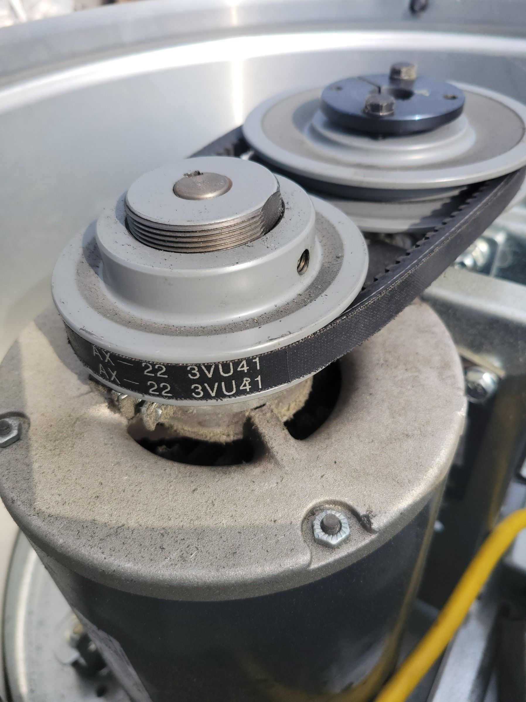 A close-up view of an electric motor shaft with a black belt connected to a pulley system.