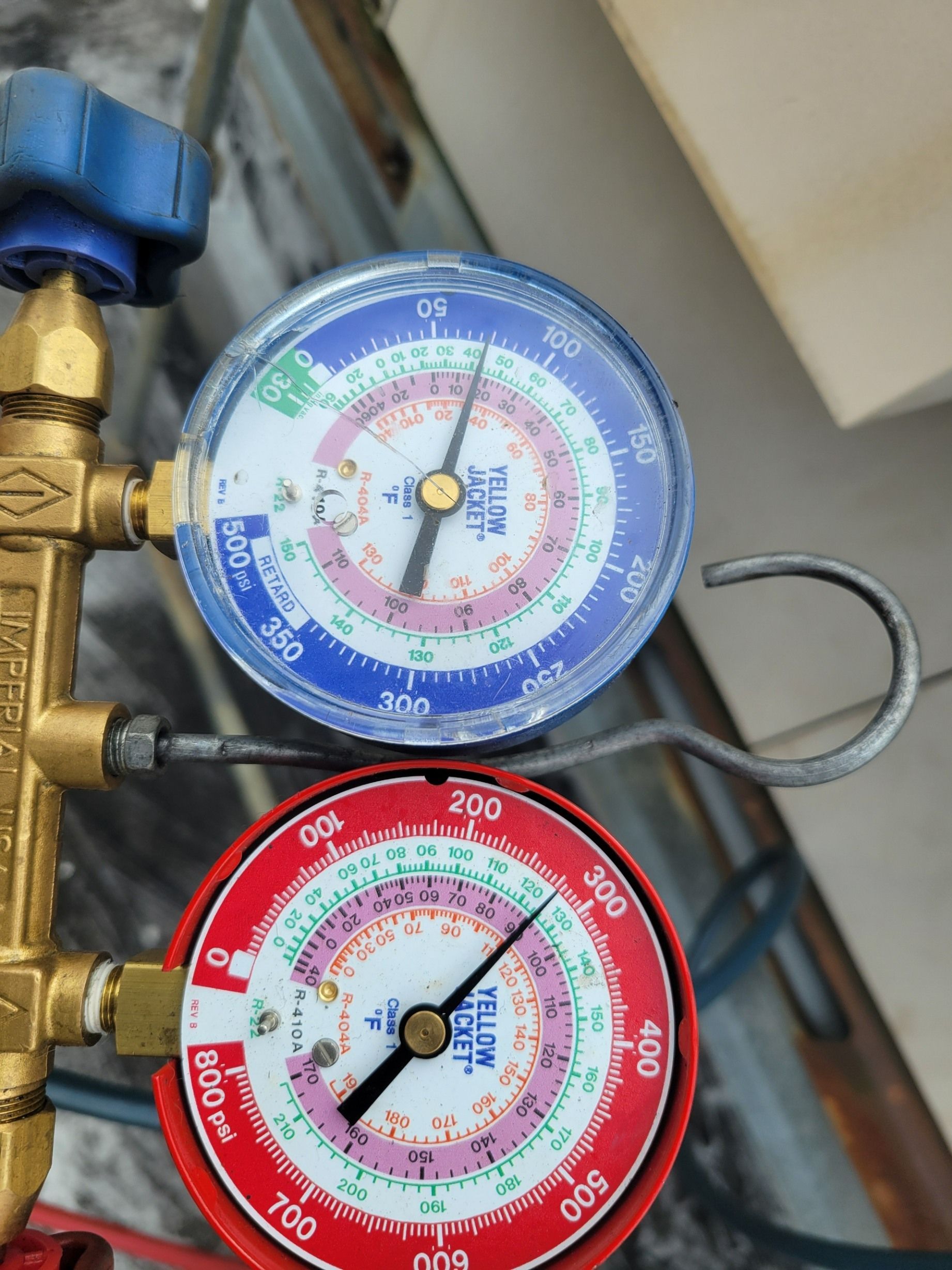 A manifold gauge set with a blue low-pressure gauge reading 75 PSI and a red high-pressure gauge reading 320 PSI.