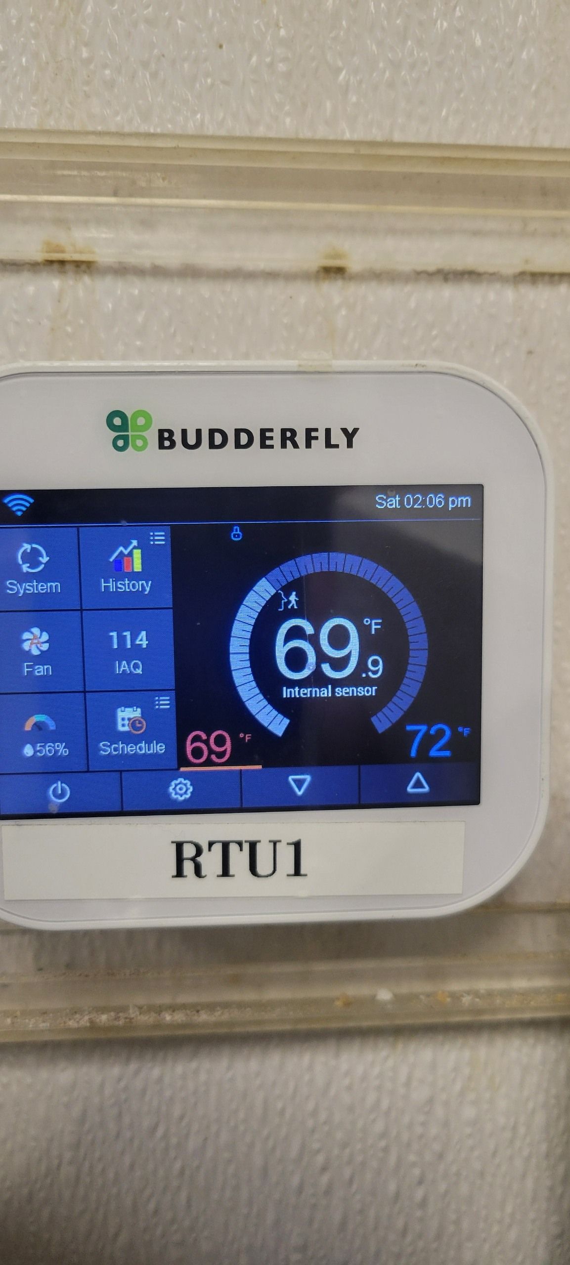A white Budderfly smart thermostat labeled 