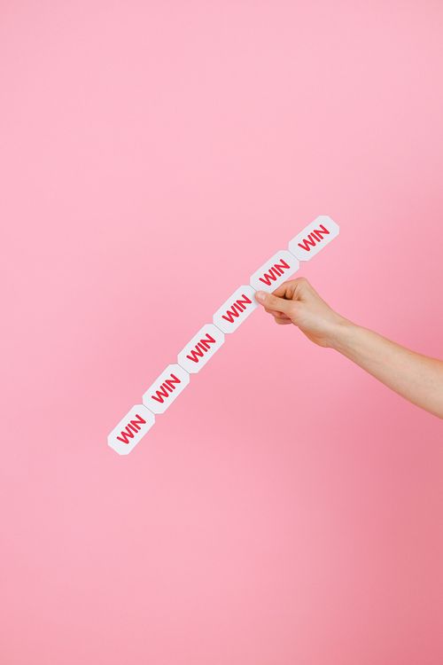 Hand holding a diagonal strip of white stickers with red text on a pink background