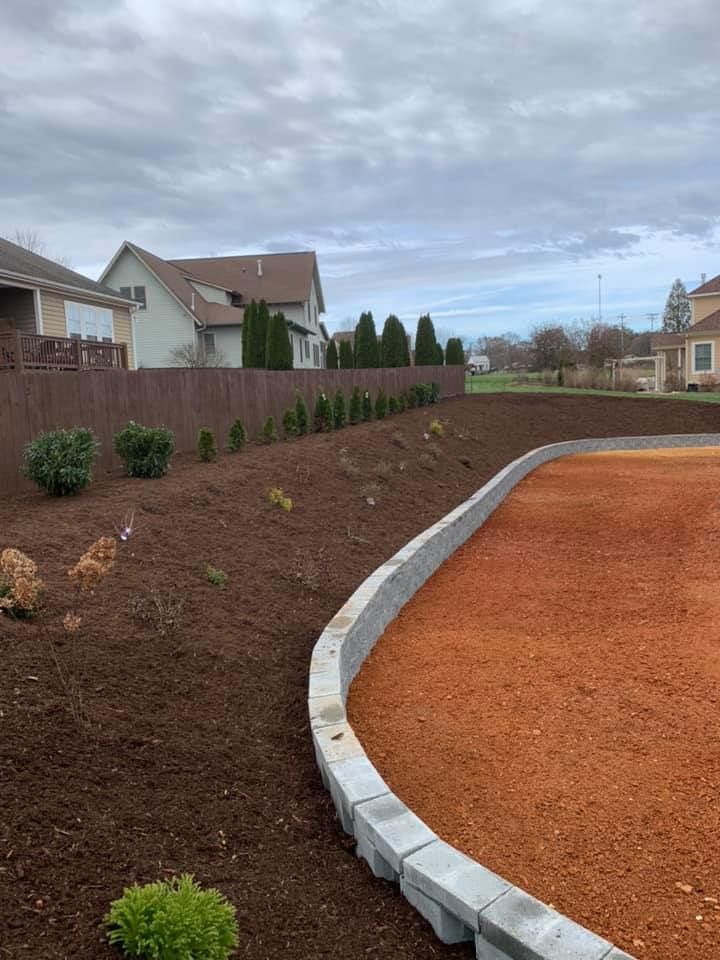 A dirt road with a brick curb and a fence in the background.