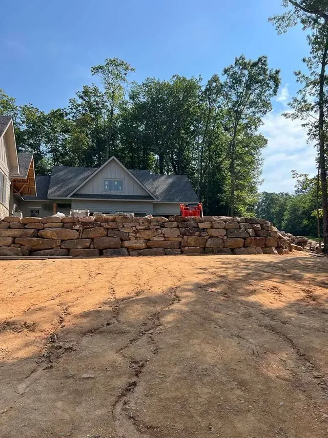 A large stone wall is being built in front of a house.
