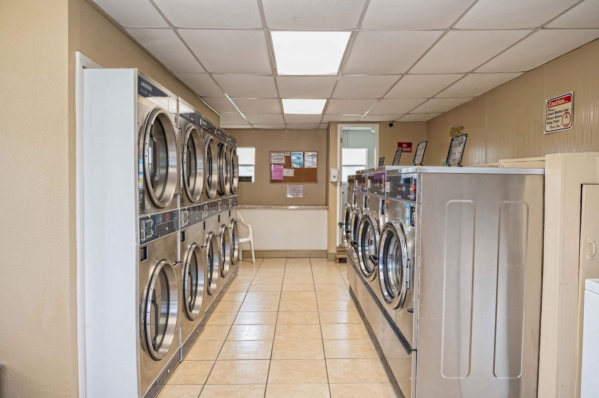 Laundry room with rows of washers and dryers under fluorescent ceiling lights