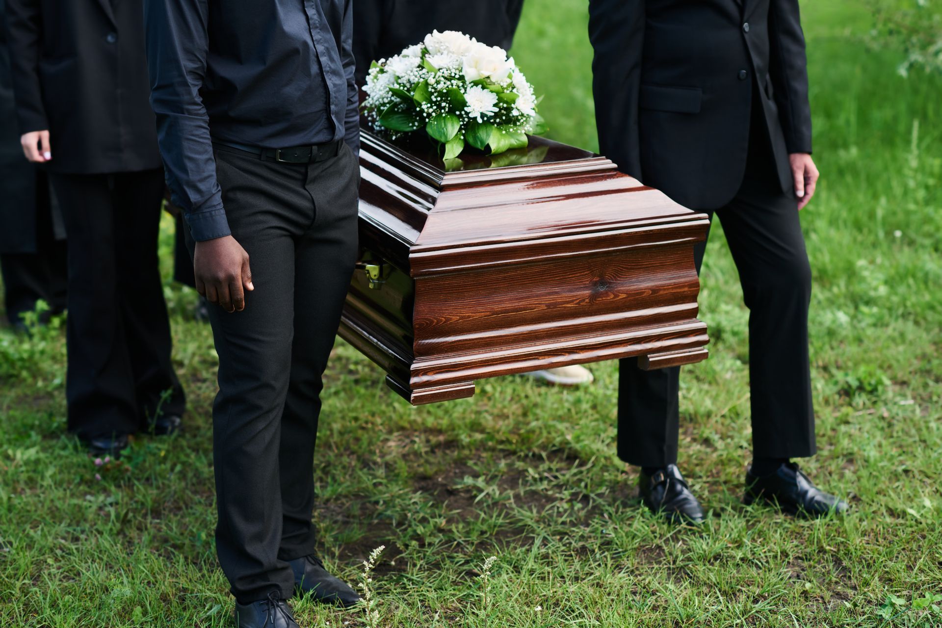 A group of people are carrying a casket at a funeral.