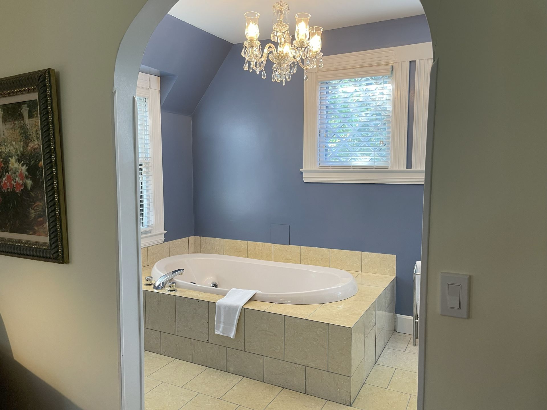 Bathroom with a built-in tub in a blue-walled alcove, framed by an arched doorway.