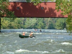 Two people in a canoe under a covered bridge
