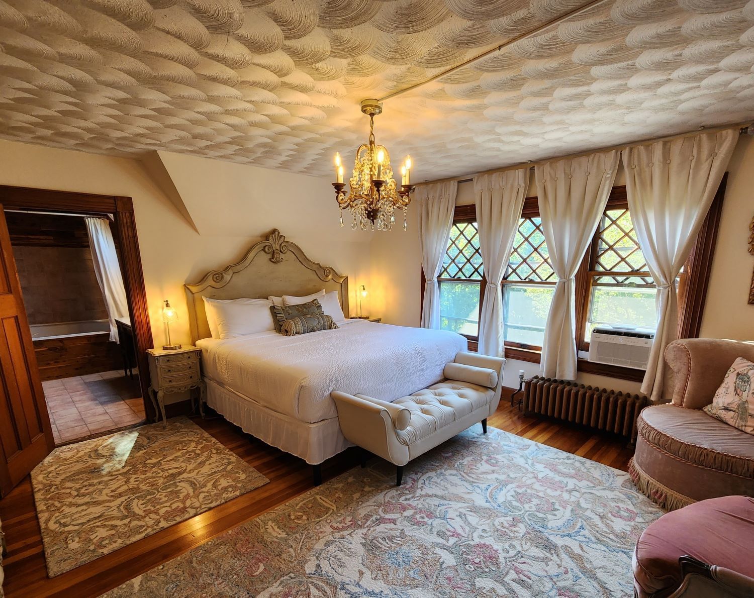 A romantic Country French bedroom at a New England Country Inn with a large bed and a chandelier.