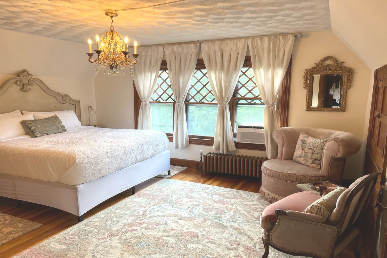 A bedroom with a large bed , chair , and chandelier.
