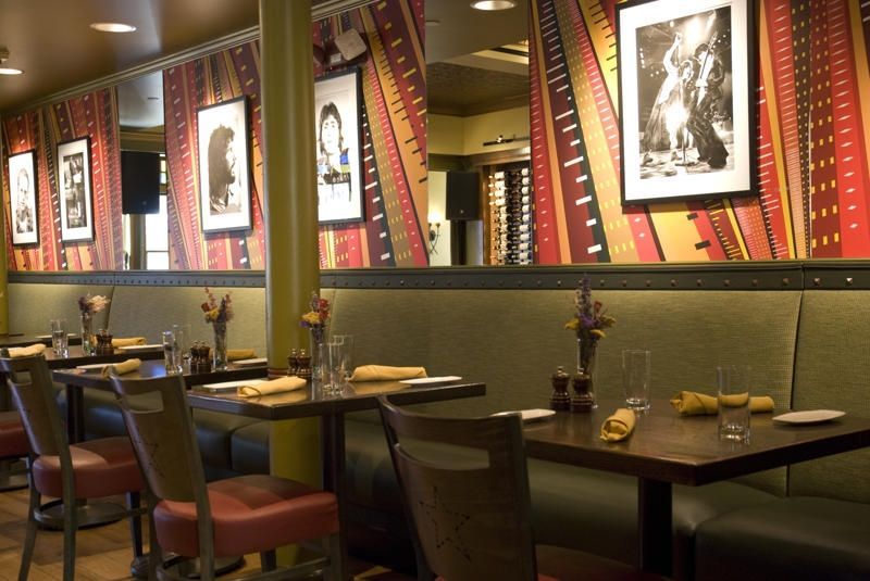 Empty restaurant dining area with dark tables, chairs, and framed black-and-white wall art.