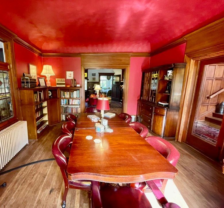 Library meeting room with red ceiling and walls, wooden table and chairs, wood cabinetry.