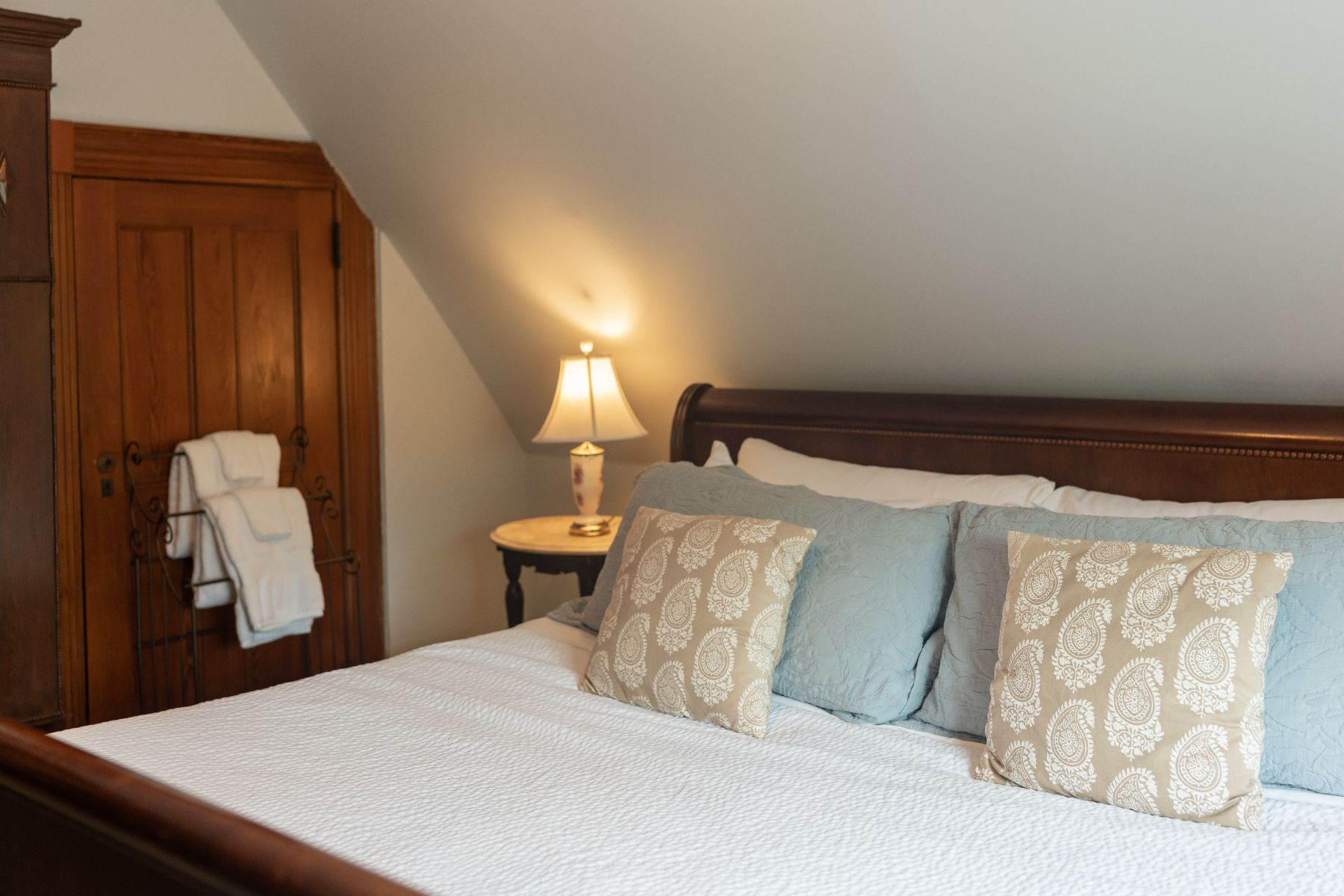 A bedroom at a New England Country Inn  with a bed , nightstand and lamp.