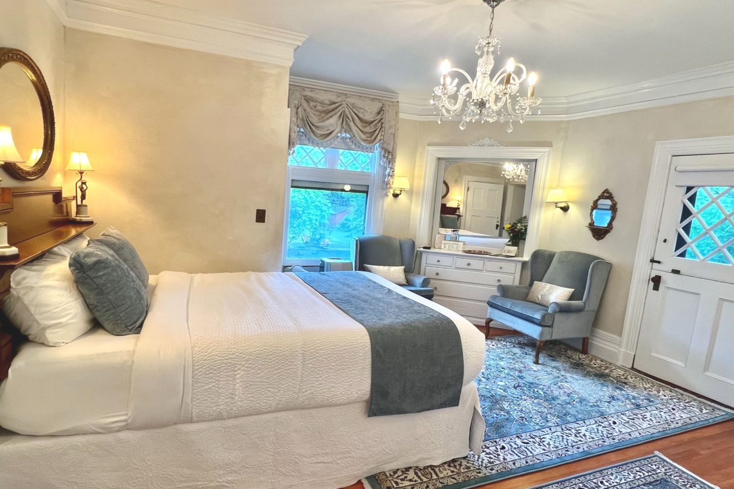 A Victorian-style bedroom at a New England Country Inn with a queen-size bed, chairs, dresser, and mirror.