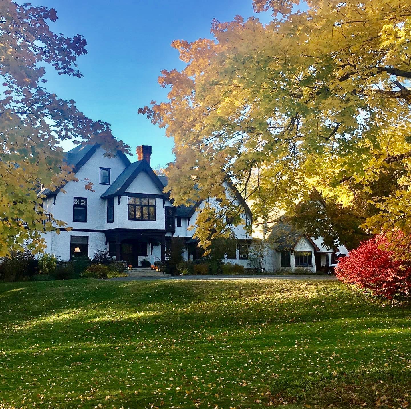 A Romantic Tudor-Style Victorian Country Inn is surrounded by trees with New England fall foliage