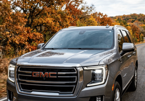 Gray GMC Yukon driving along a scenic road surrounded by colorful fall foliage