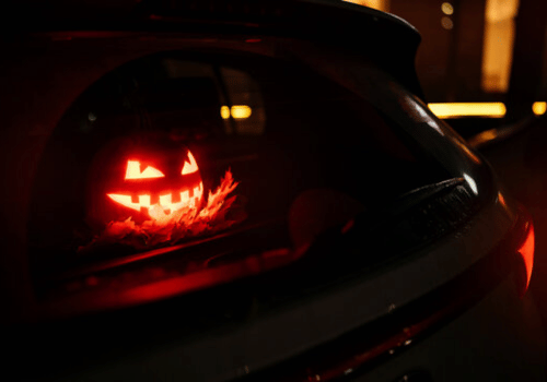 Glowing jack-o'-lantern face seen through a dark car window at night