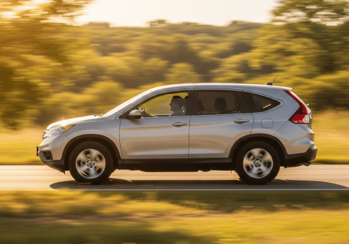 Silver SUV driving on a road with motion-blurred trees in the background