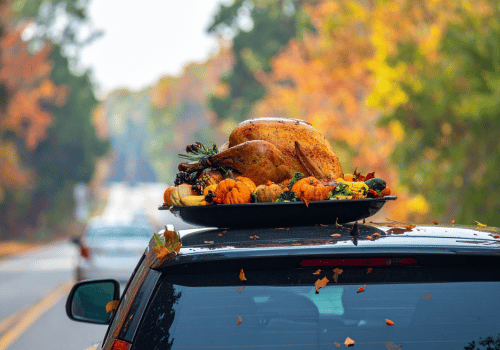 Roasted turkey on a car roof rack driving through an autumn tree-lined road with falling leaves
