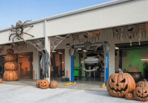 Auto repair shop decorated for Halloween with giant spiders, cobwebs, ghosts, and pumpkins