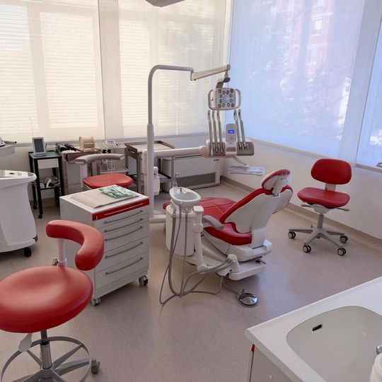 Studio dentistico moderno con poltrone rosse e bianche, attrezzature e grandi finestre
