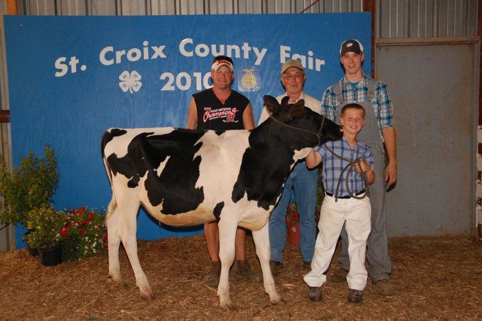 People posing with a black and white calf at the St. Croix County Fair, 2010.