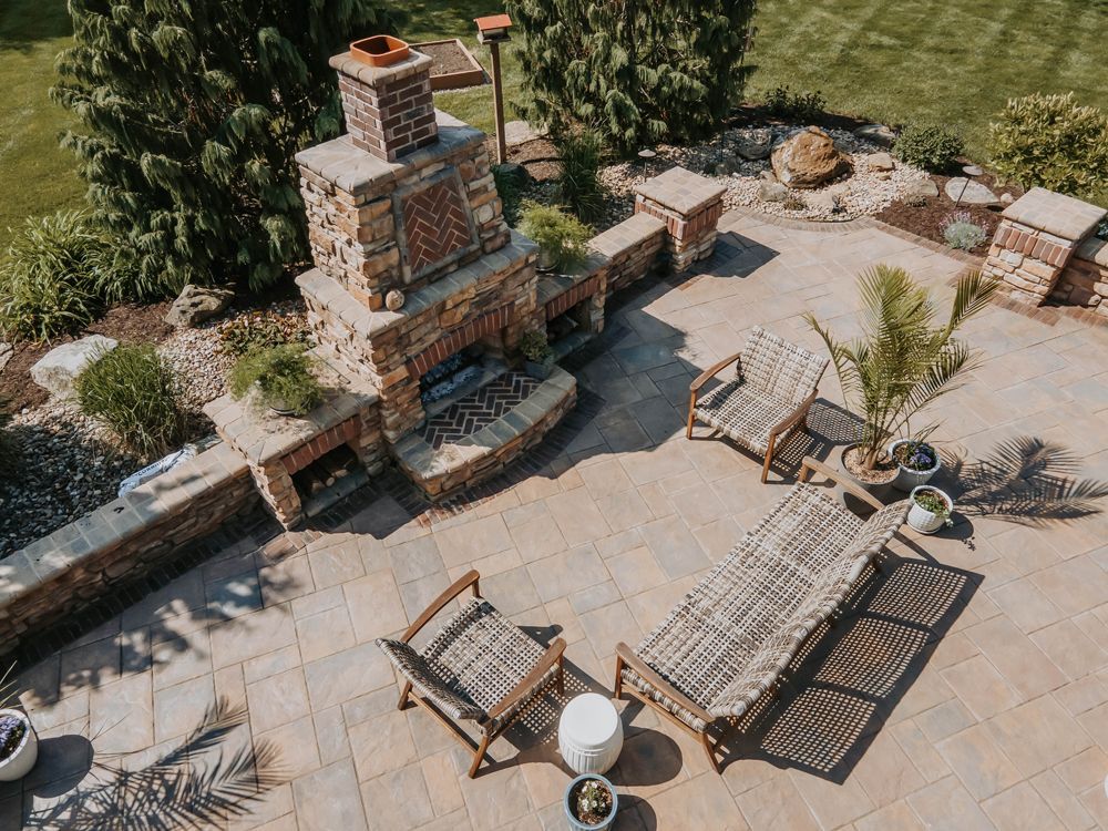 Aerial view of a brick patio with an outdoor fireplace and seating.