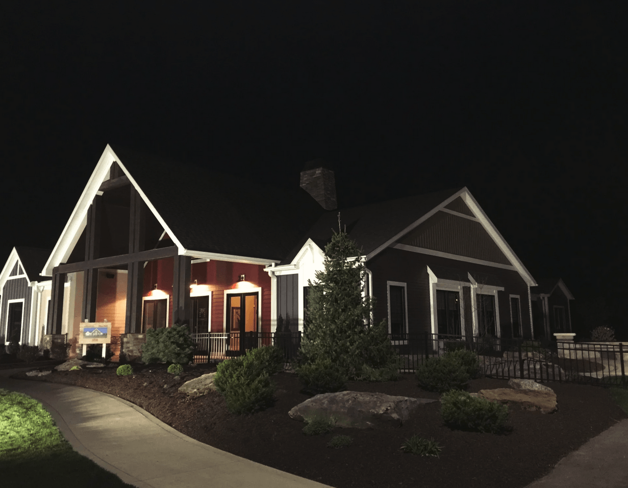A dark-colored building at night with a prominent gable roof and outdoor lighting, likely a restaurant or event space.