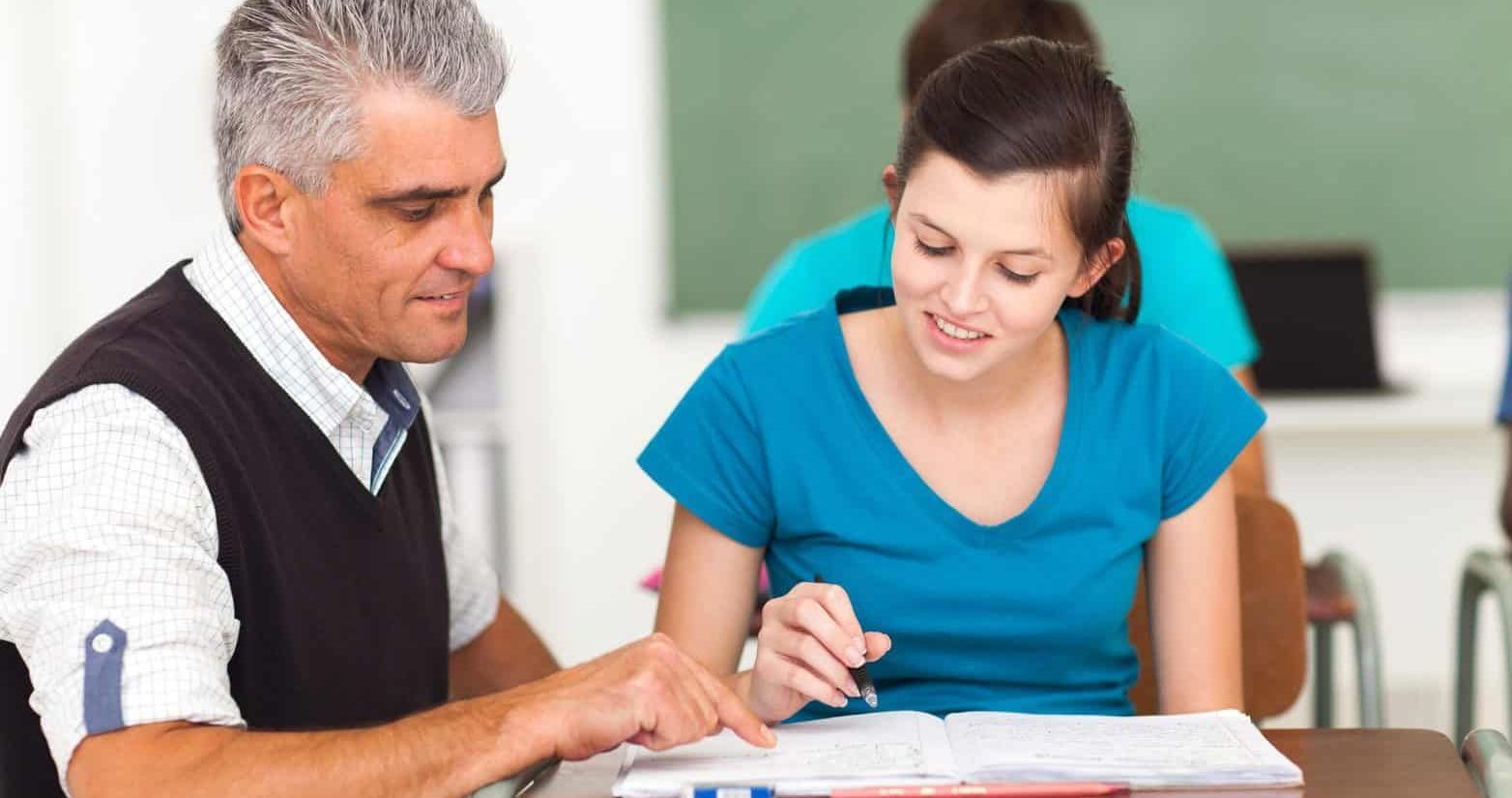 A teacher is helping a student with her homework in a classroom.