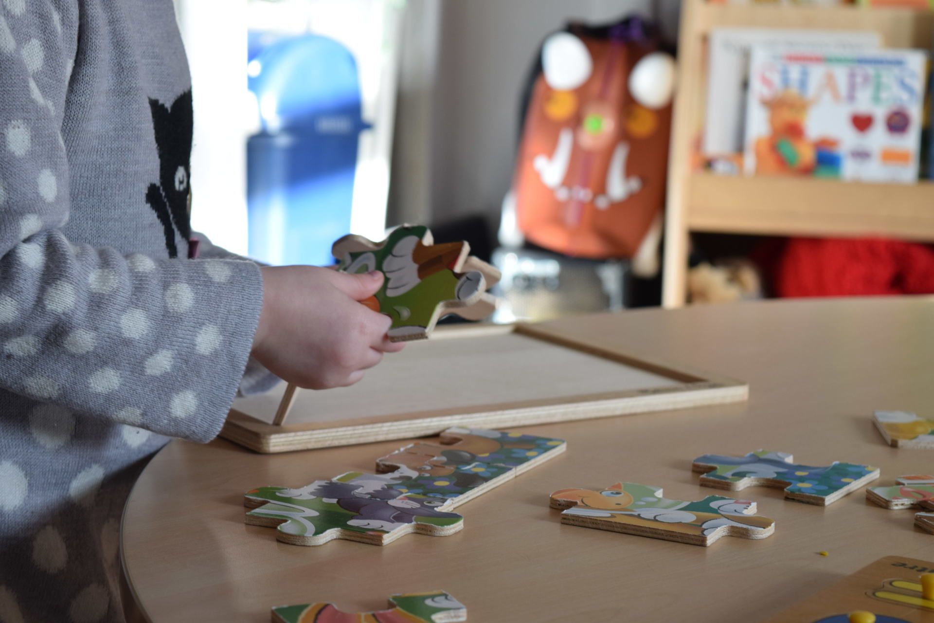 A child is sitting at a table playing with puzzles.