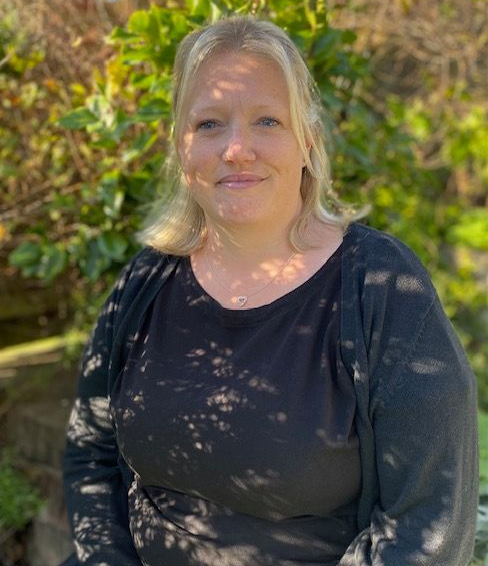 A woman in a black shirt is sitting in front of a tree.
