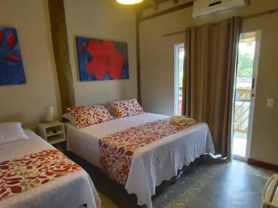 Um quarto de hotel com duas camas, roupa de cama floral, obras de arte azuis na parede e uma porta de vidro que dá para uma varanda.